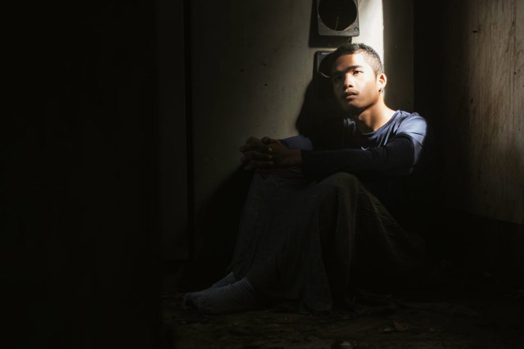 Man sitting alone in a dark room, highlighting male isolation and untreated mental health struggles.