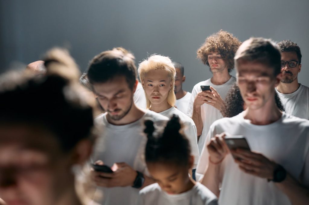 A group of men standing close together while looking at their phones, appearing emotionally disconnected—illustrating modern male isolation and the importance of male support groups.