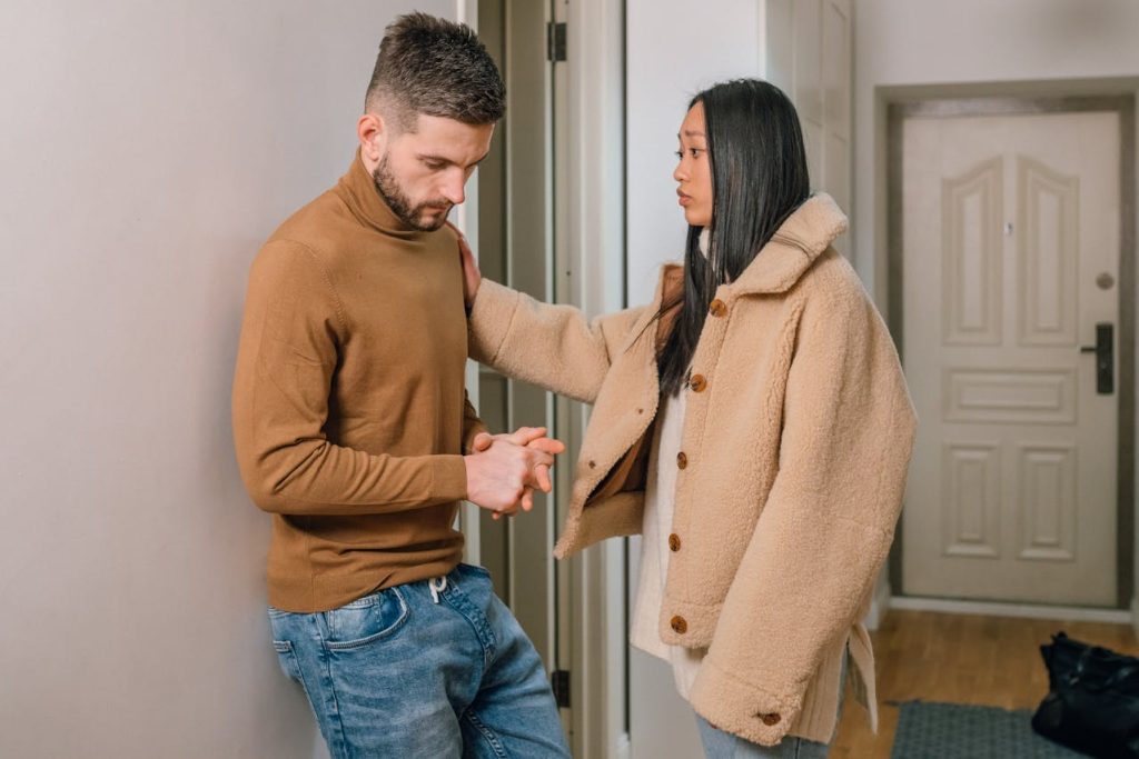 Woman gently supporting a distressed man during an emotional conversation, symbolizing encouragement and guidance toward seeking therapy.