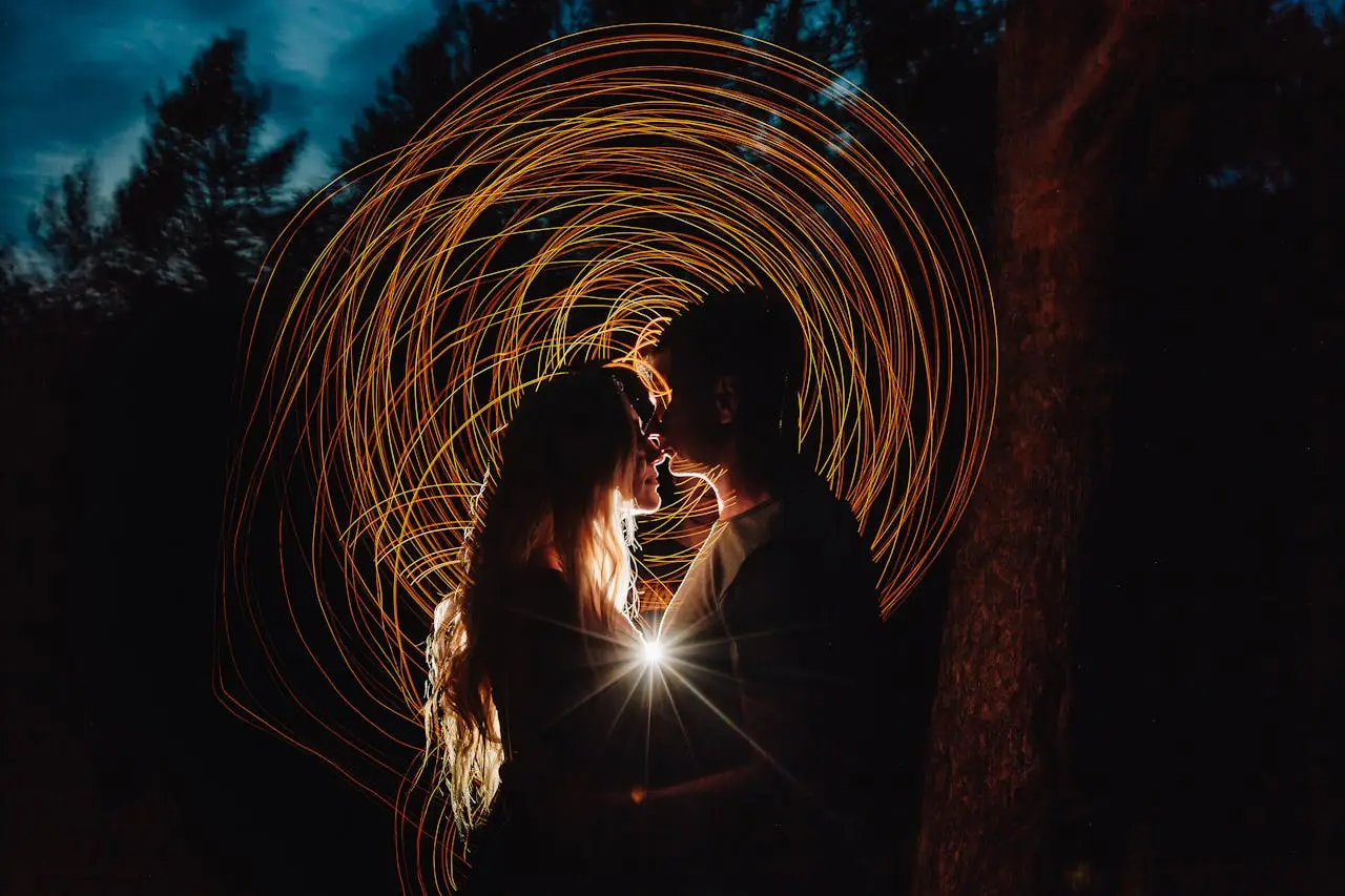 Couple standing close at night with swirling golden light patterns behind them, symbolizing emotional intensity and the distinction between genuine connection and unhealthy projections.