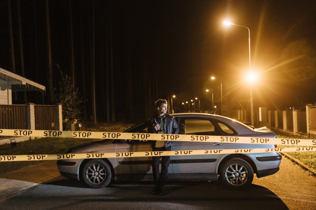 Man standing behind “STOP” boundary tape beside a car at night, symbolizing personal non-negotiables and firm life boundaries.
