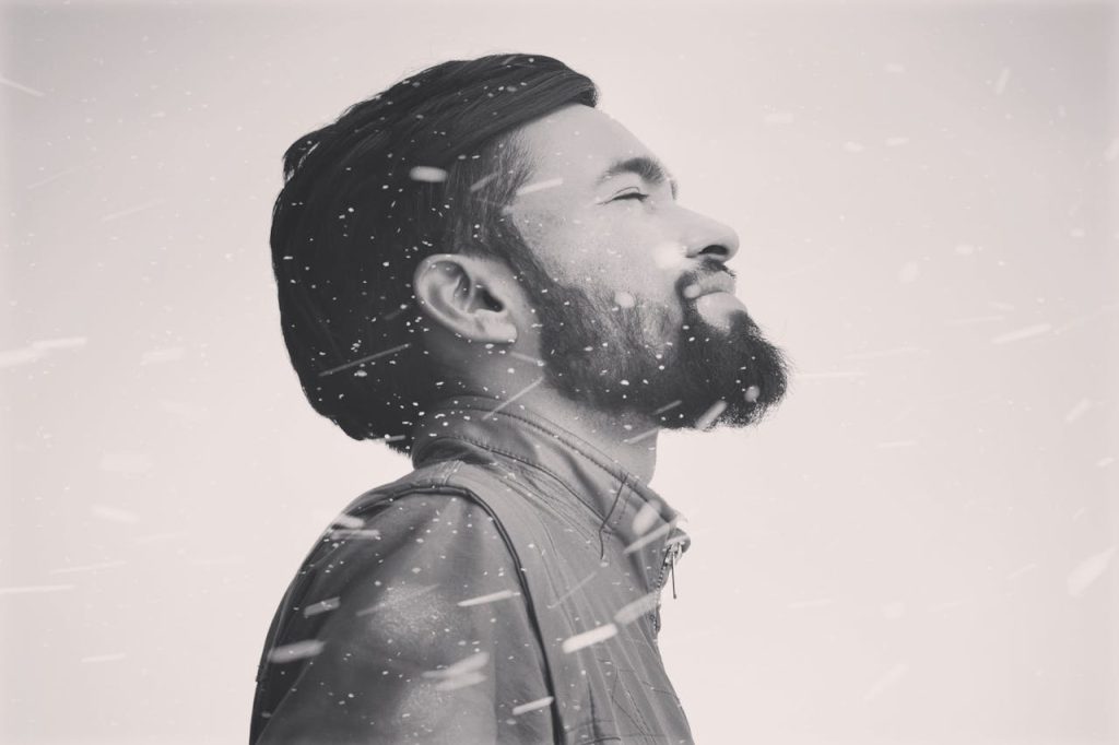 Calm man standing with eyes closed in the midst of swirling snow, symbolizing Stoic composure and inner stability during life's chaos.
