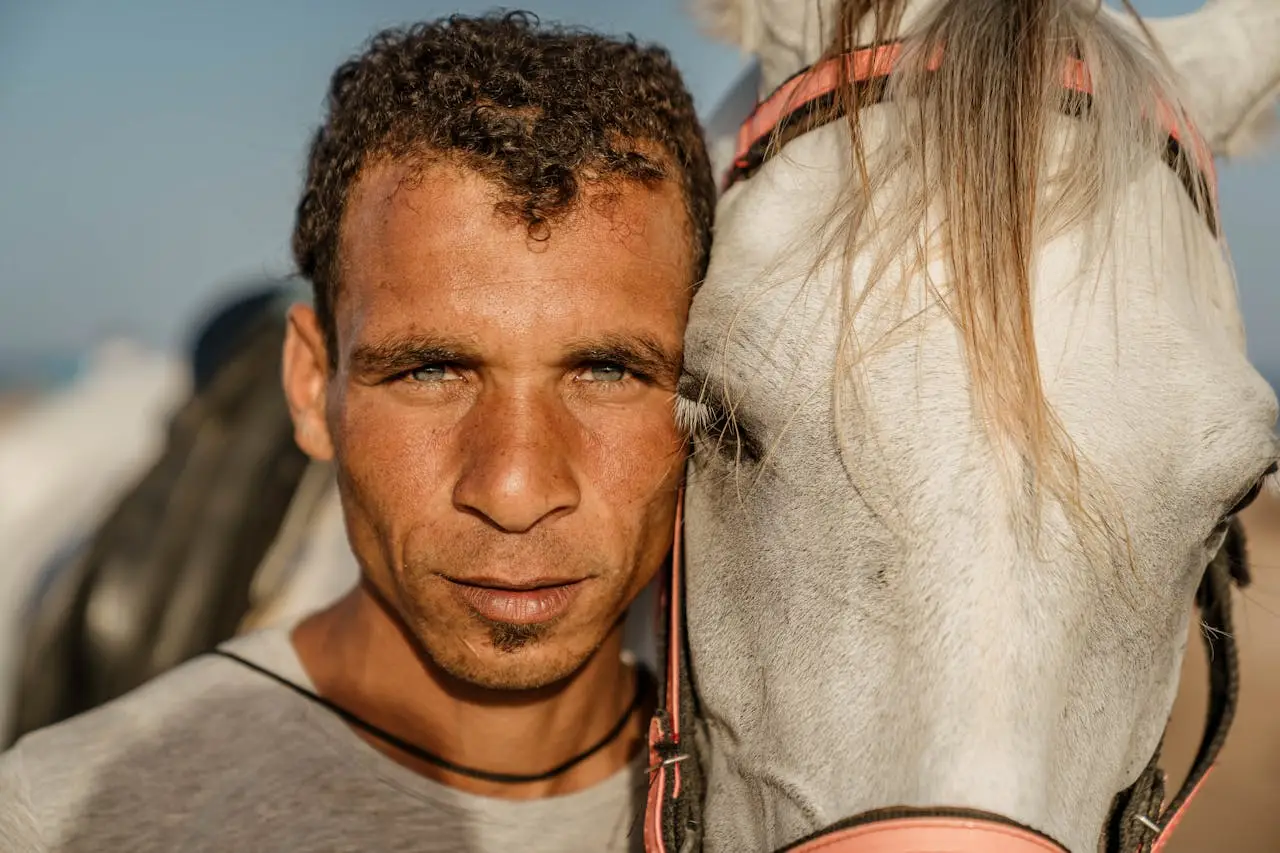 Man standing closely beside a white horse, symbolizing loyalty, responsibility, and masculine commitment.