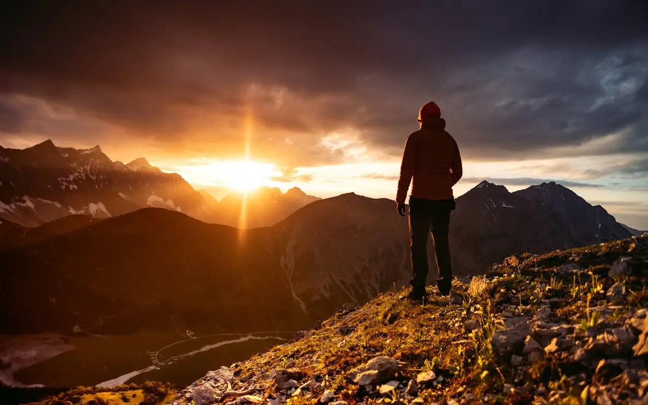Man standing on a mountain at sunrise, symbolizing strength, clarity, and the elevated journey of modern masculinity promoted by Masculinitism.