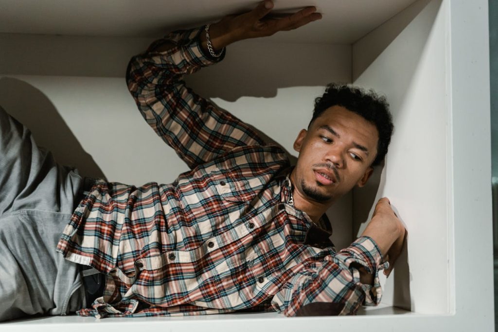 A man cramped inside a small box, symbolizing the restrictive expectations of the Man Box and unhealthy masculinity norms.