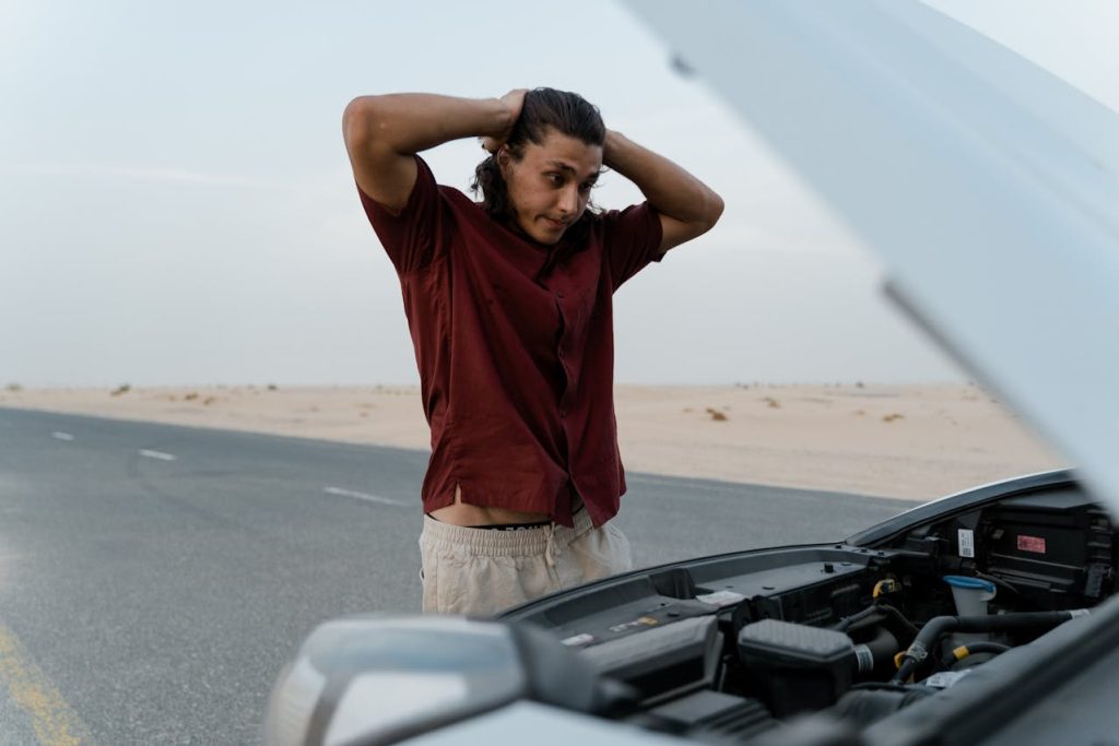 Man struggling alone to fix a broken car in the desert, symbolizing why men avoid therapy and rely on toxic self-reliance.