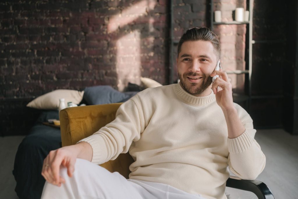 A man sitting comfortably at home making a phone call, symbolizing taking proactive steps to prepare for emotional challenges.