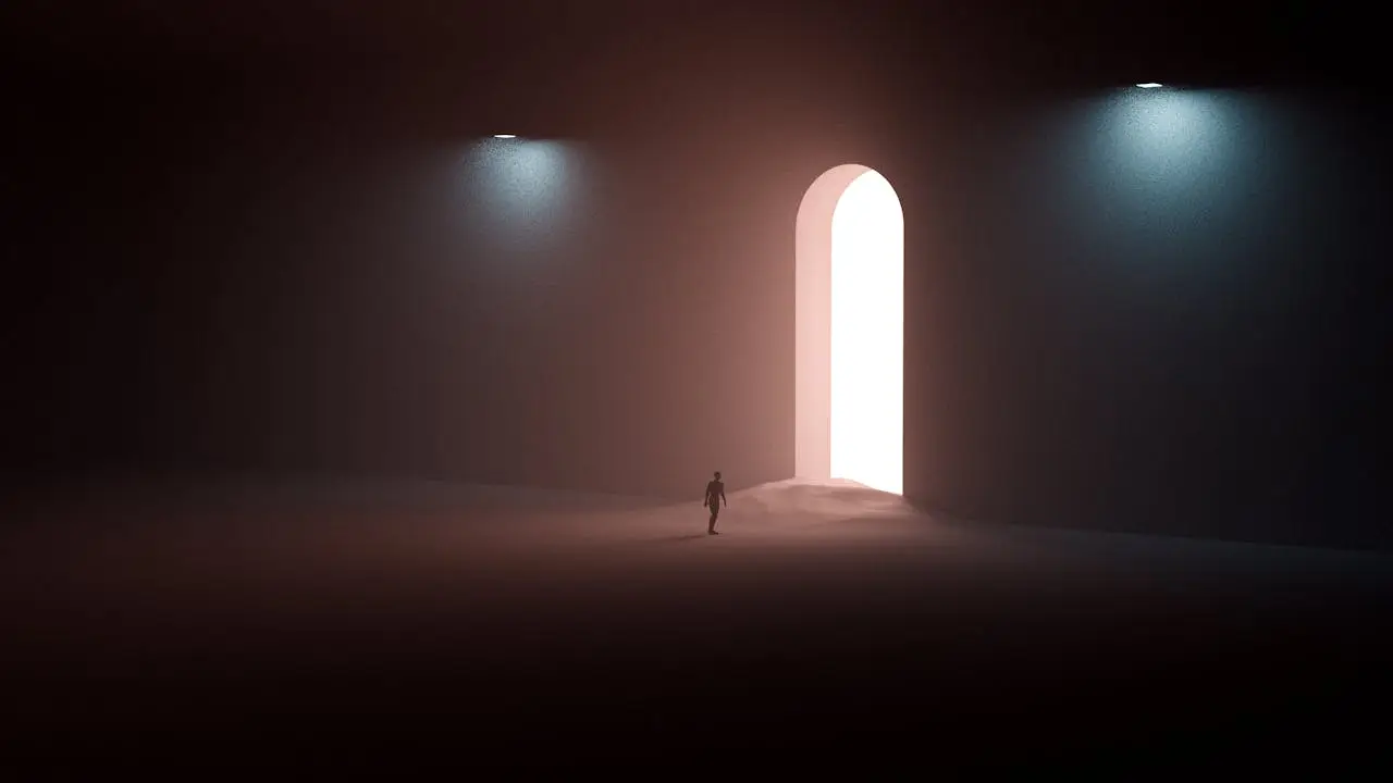 Silhouette of a man walking alone toward a bright doorway in a vast dark space, symbolizing personal responsibility and the solitary journey of masculine growth.
