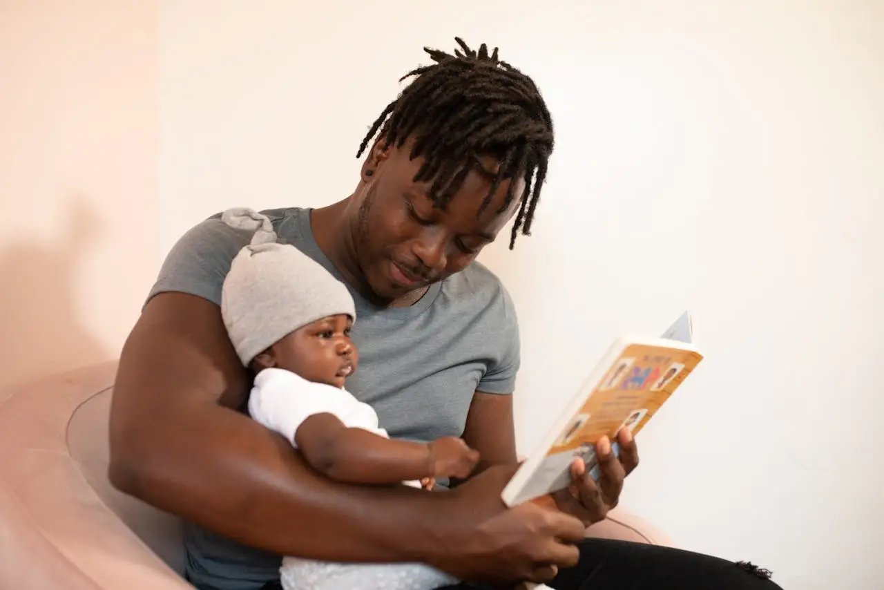 Father reading to his baby, symbolizing mature masculinity expressed through care, presence, and responsibility.
