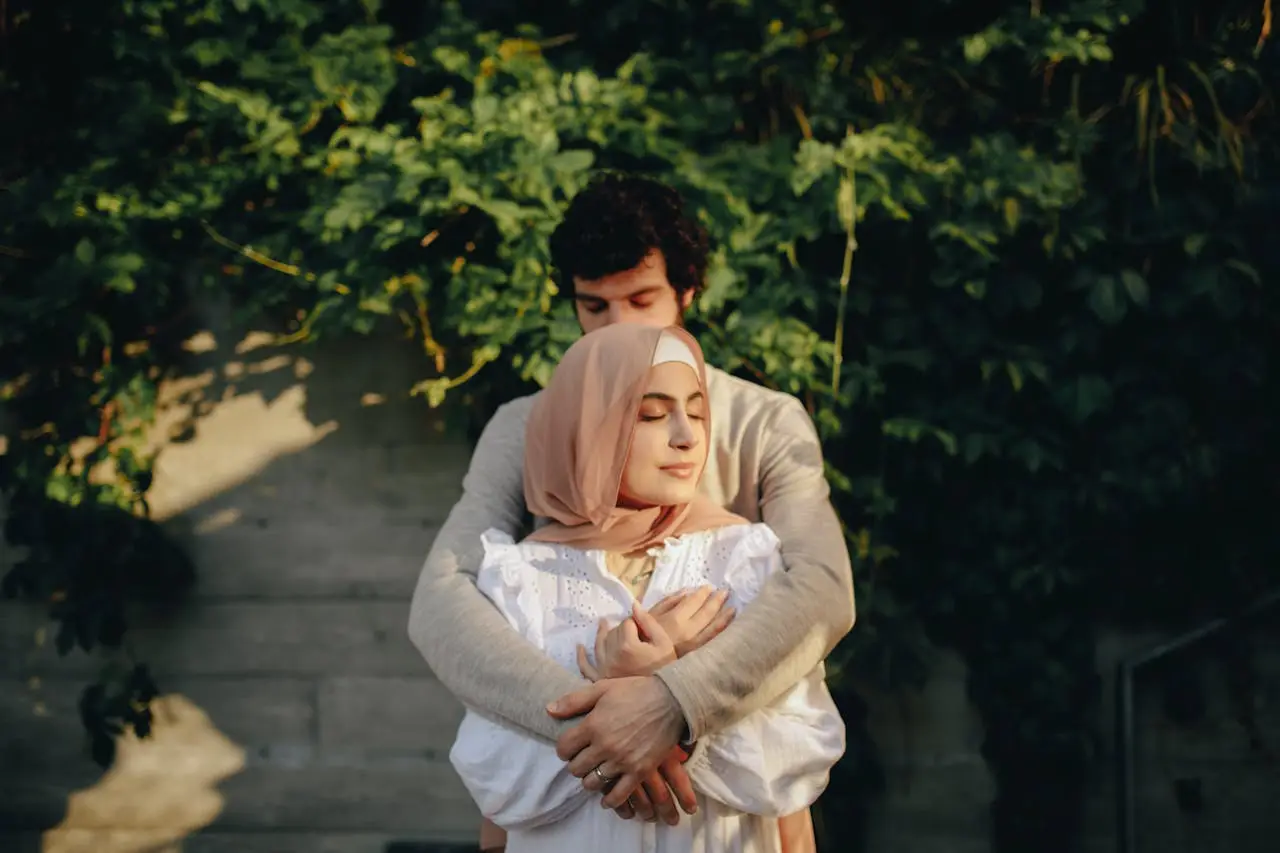 Man gently embracing a woman wearing a hijab as she rests peacefully, symbolizing trust, partnership, and shared growth.
