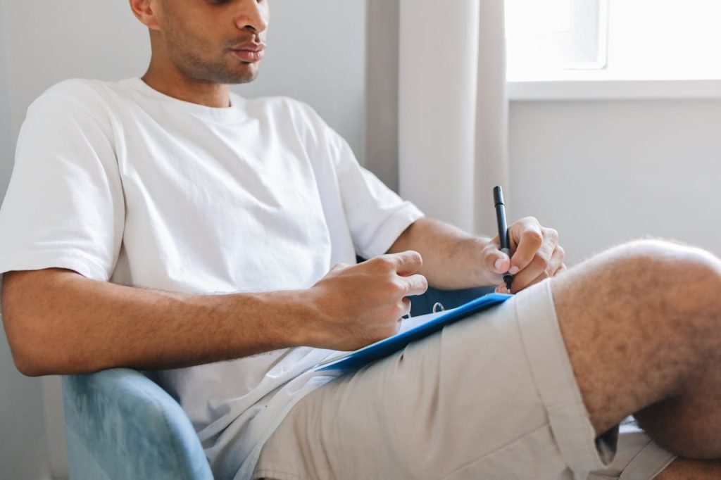 Man reviewing notes with a checklist while reflecting, symbolizing regular accountability to a personal philosophy.