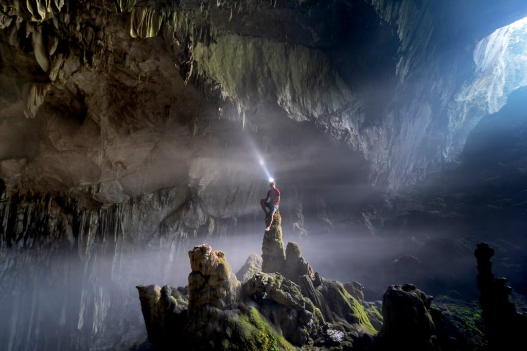 Man standing inside a vast cave with a headlamp shining through darkness, symbolizing finding inner direction and an anchor in life.