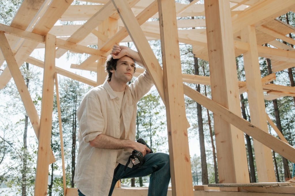 Man pausing thoughtfully during a construction project, symbolizing the process of building a personal philosophy.