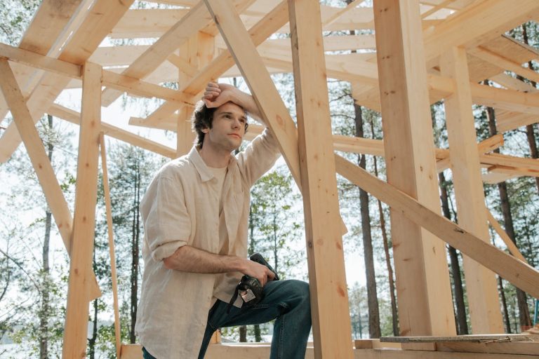 Man pausing thoughtfully during a construction project, symbolizing the process of building a personal philosophy.