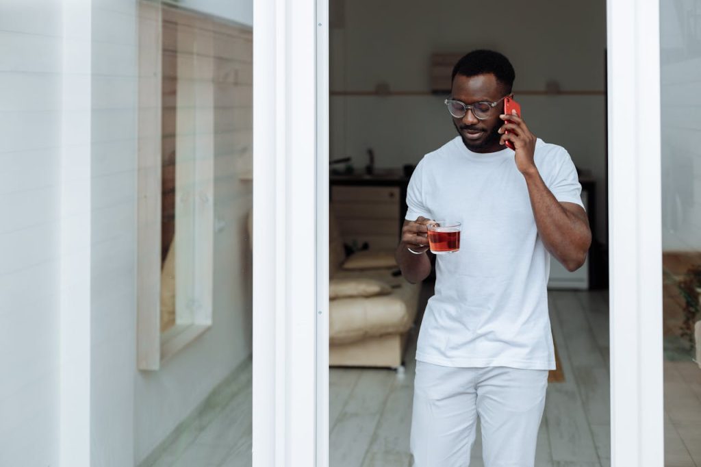 Man standing calmly with tea while talking on the phone, representing grounded integrity in mindful dating for men.