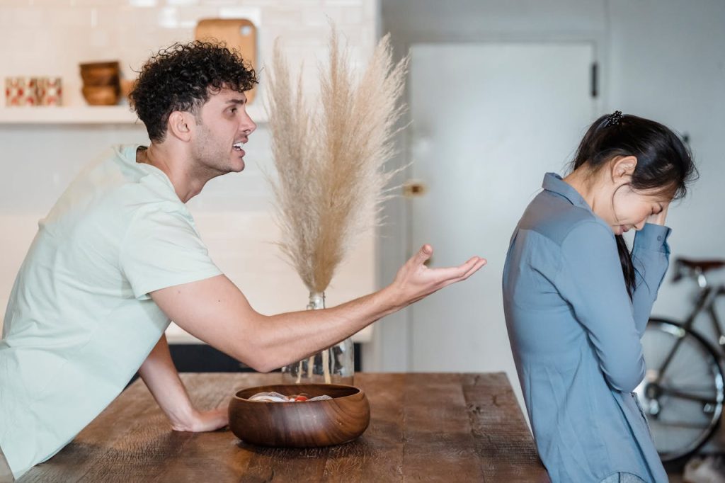 A man yelling at a distressed woman in a kitchen, illustrating relationship conflict and the emotional strain caused by poor communication.