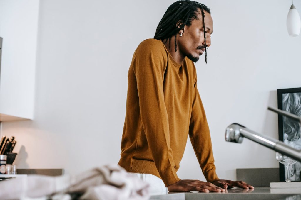 Man leaning on a counter with a distant, unfocused expression, illustrating men and emotional numbness.