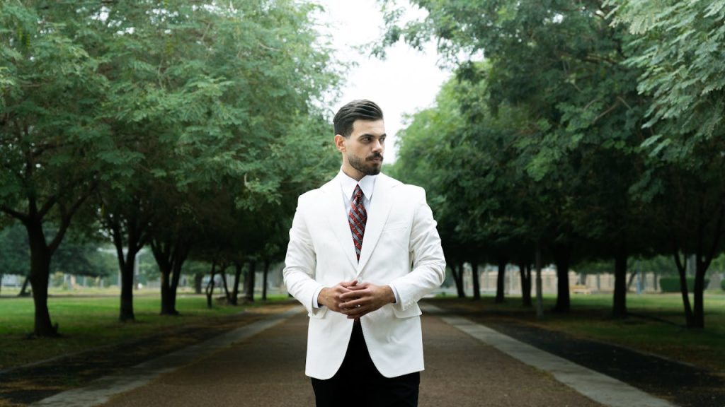 A well-dressed man standing alone on a tree-lined path, symbolizing Nice Guy syndrome and the journey from approval-seeking to self-respect and assertiveness.