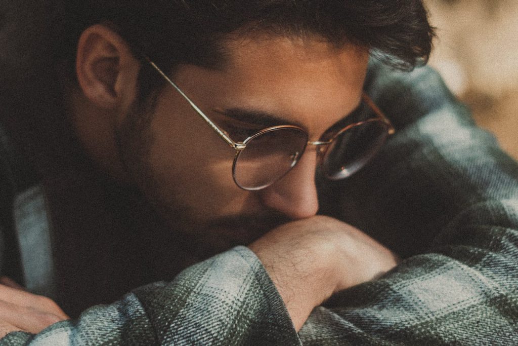 A reflective man resting his head on his arm, symbolizing the balance between stoic strength and emotional vulnerability.