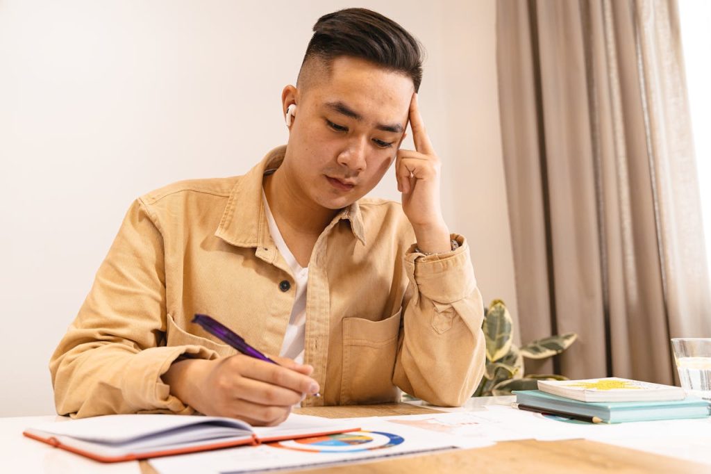 Man sitting at a desk journaling in natural light, reflecting on personal patterns shaped by childhood experiences.