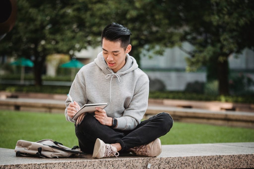 Man sitting outdoors journaling in a park, representing reflection, self-discovery, and finding purpose as a man.