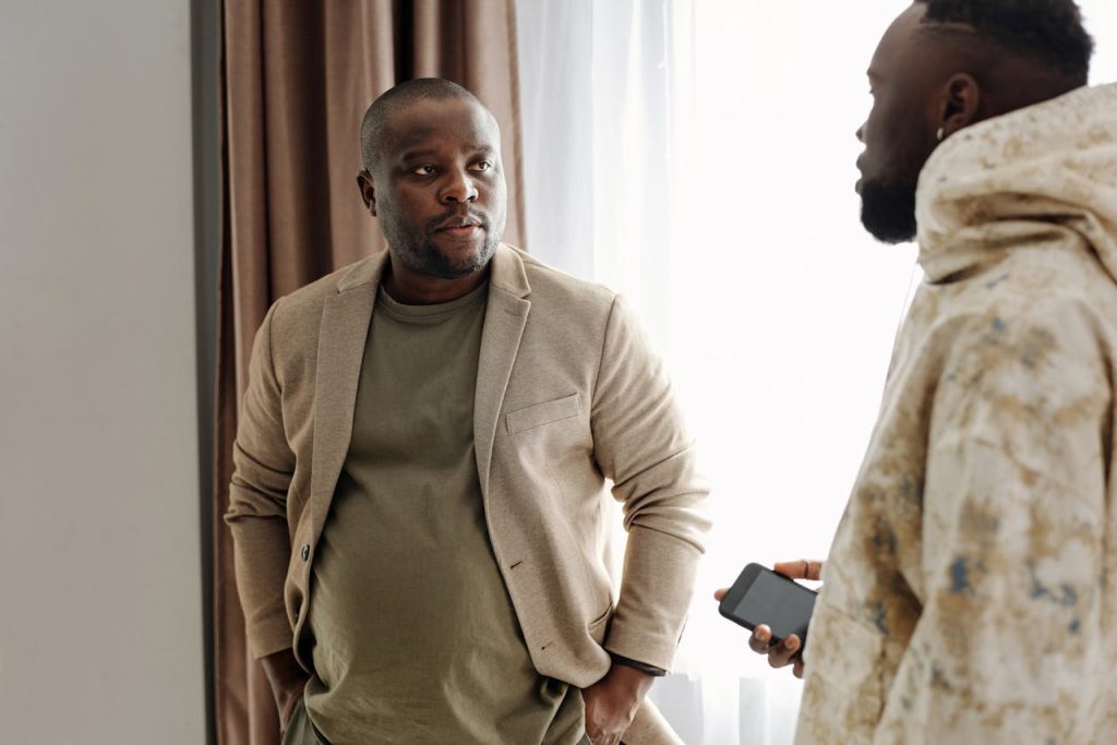 Two men having an open, honest conversation indoors, showing trust and healthy emotional vulnerability.
