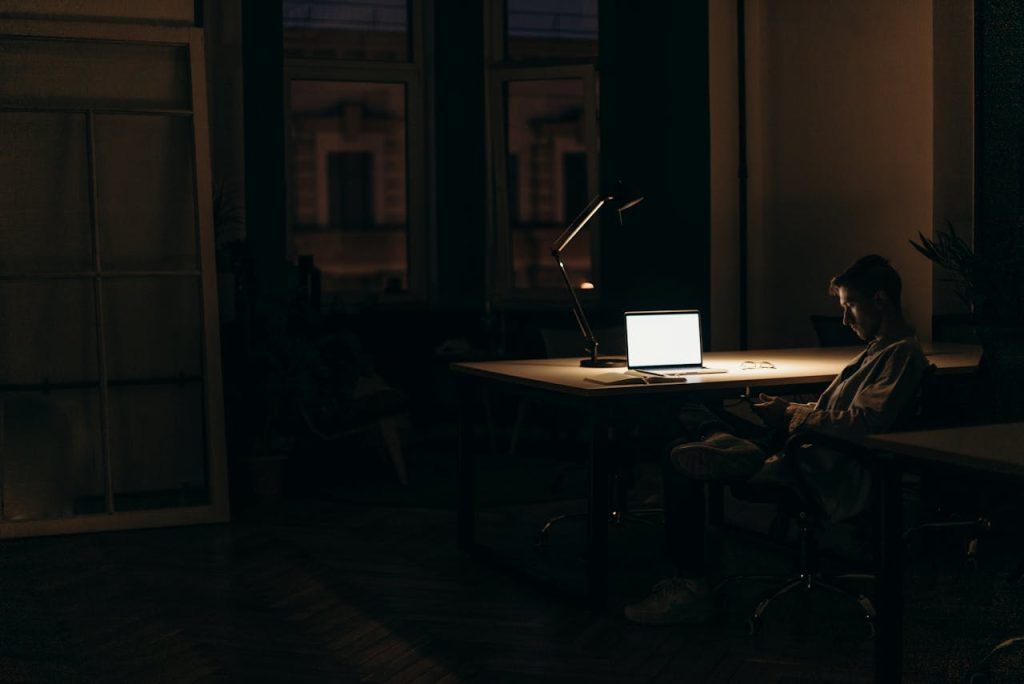 Man sitting alone at a desk at night with a laptop, symbolizing external success but inner emptiness while searching for purpose as a man.