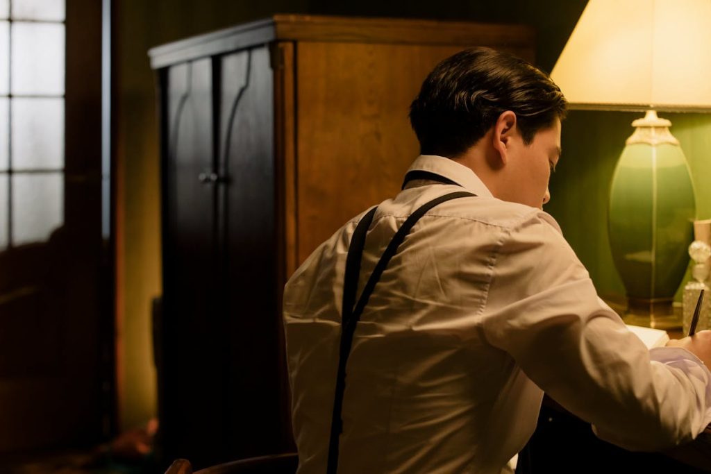 A man writing in a journal by lamplight, symbolizing shadow work for men through reflective journaling and self-examination.