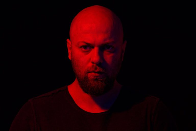Portrait of a man in dramatic red lighting representing the strong silent archetype and its emotional impact.
