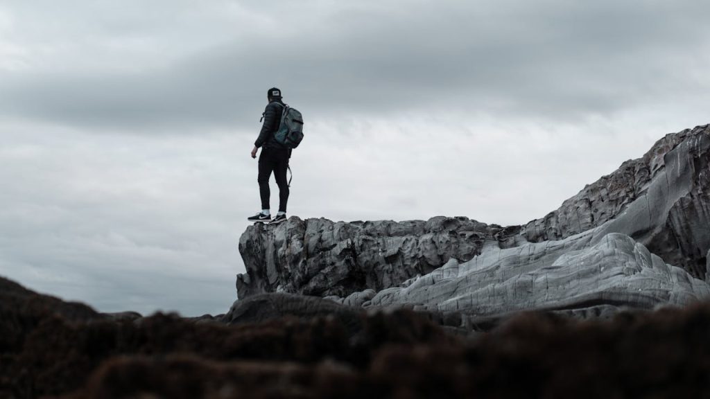 Man standing confidently on a rocky cliff, calm and grounded, symbolizing mature masculinity without posturing.