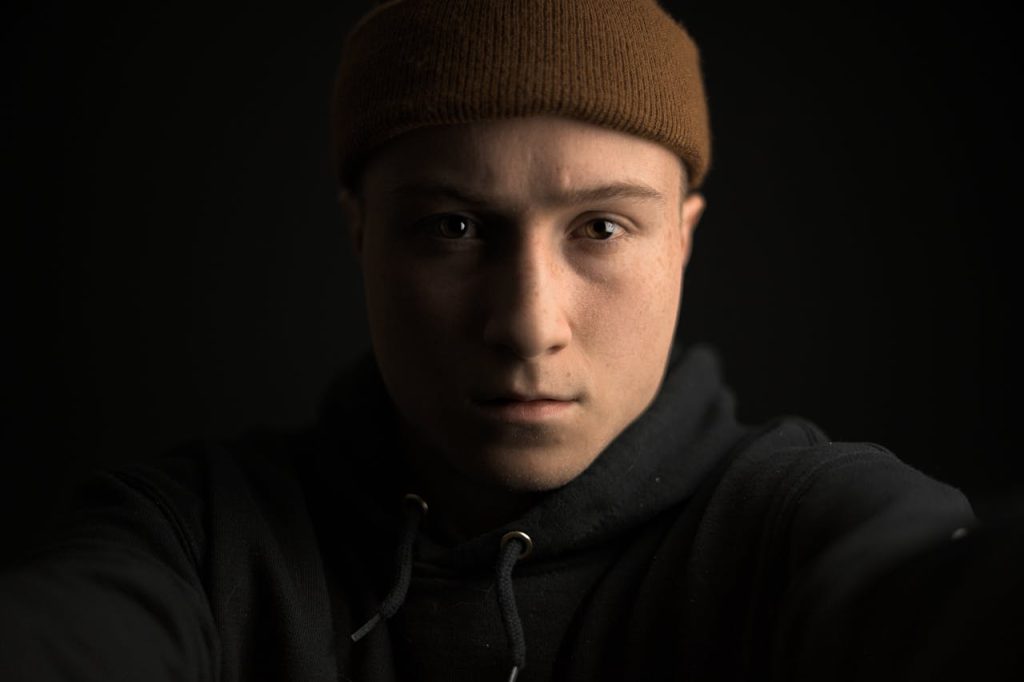 Close-up portrait of a man in low light, conveying emotional guardedness and the long-term impact of childhood trauma on men’s mental health.