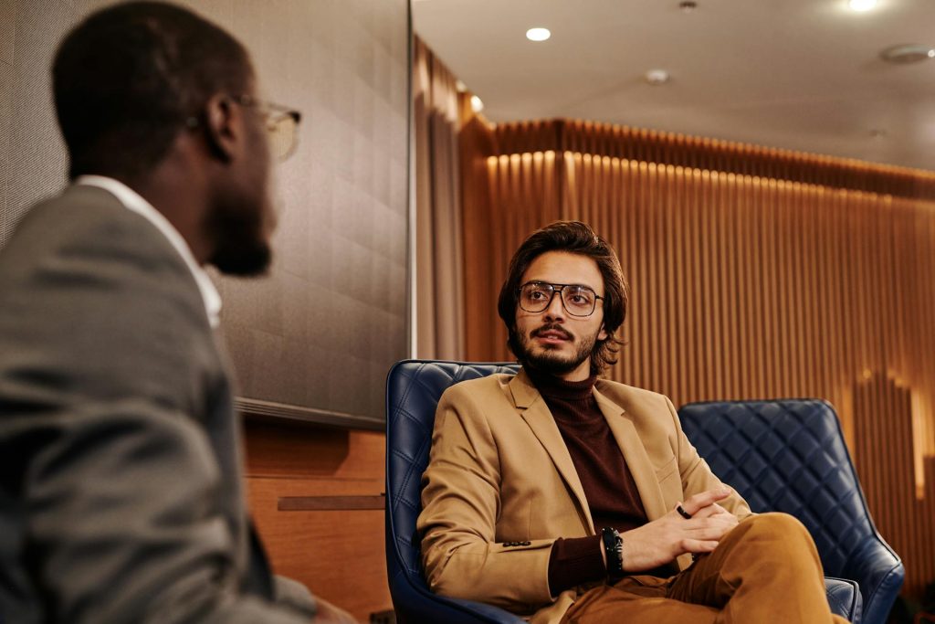 A man attentively listening to a mentor during a serious conversation, symbolizing the importance of choosing trustworthy people to ask for help.