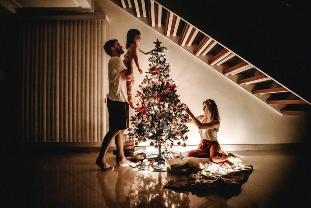 Father and mother decorating a Christmas tree with their child at home, symbolizing spiritual leadership at home through presence, values, and family connection.