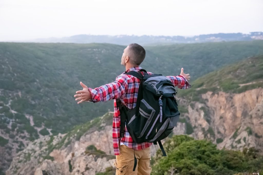 Man standing on a mountain with arms open wide, symbolizing the freedom and emotional release that comes from forgiving your father.