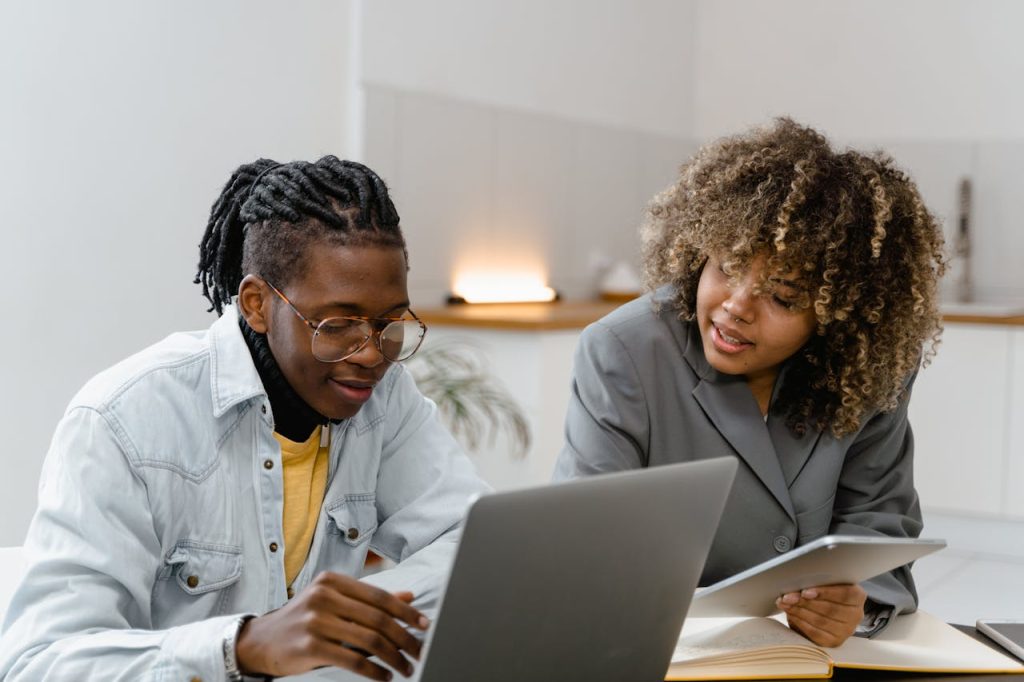 Two people collaborating over a laptop and tablet, symbolizing how one connection can lead to broader support.