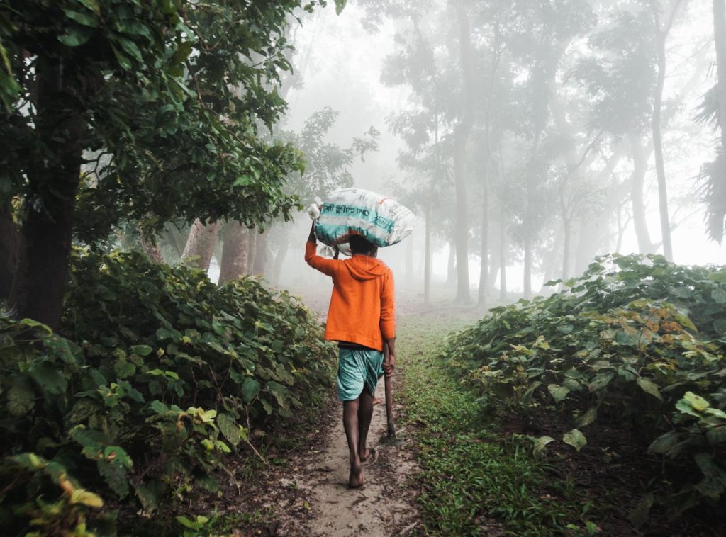 Person walking barefoot along a misty forest path carrying a heavy load, symbolizing the emotional weight carried before forgiving your father.