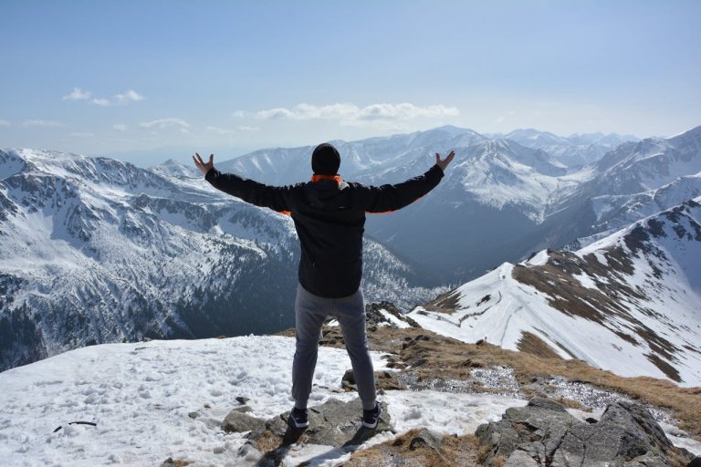 Man standing on a mountain peak with arms raised, symbolizing freedom, recovery, and breaking free from porn addiction.