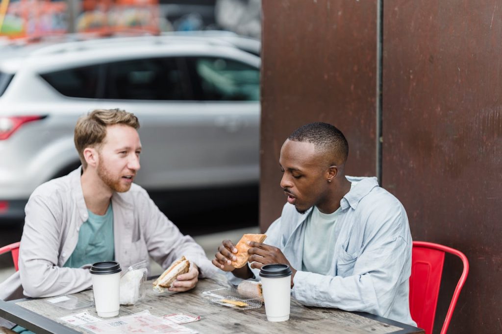 Two men talking over coffee, one listening supportively as the other opens up about personal struggles and self-forgiveness.
