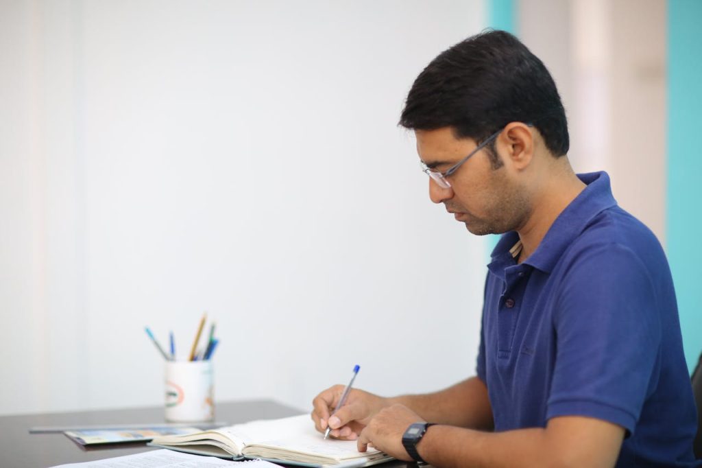 Man writing in a journal at a desk, symbolizing the reflective inner work involved in forgiving your father.