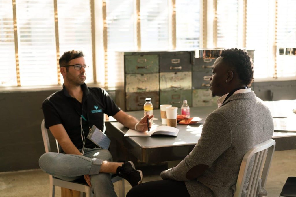 Two men engaged in a focused workplace conversation, demonstrating emotional intelligence in men through active listening, empathy, and calm communication.