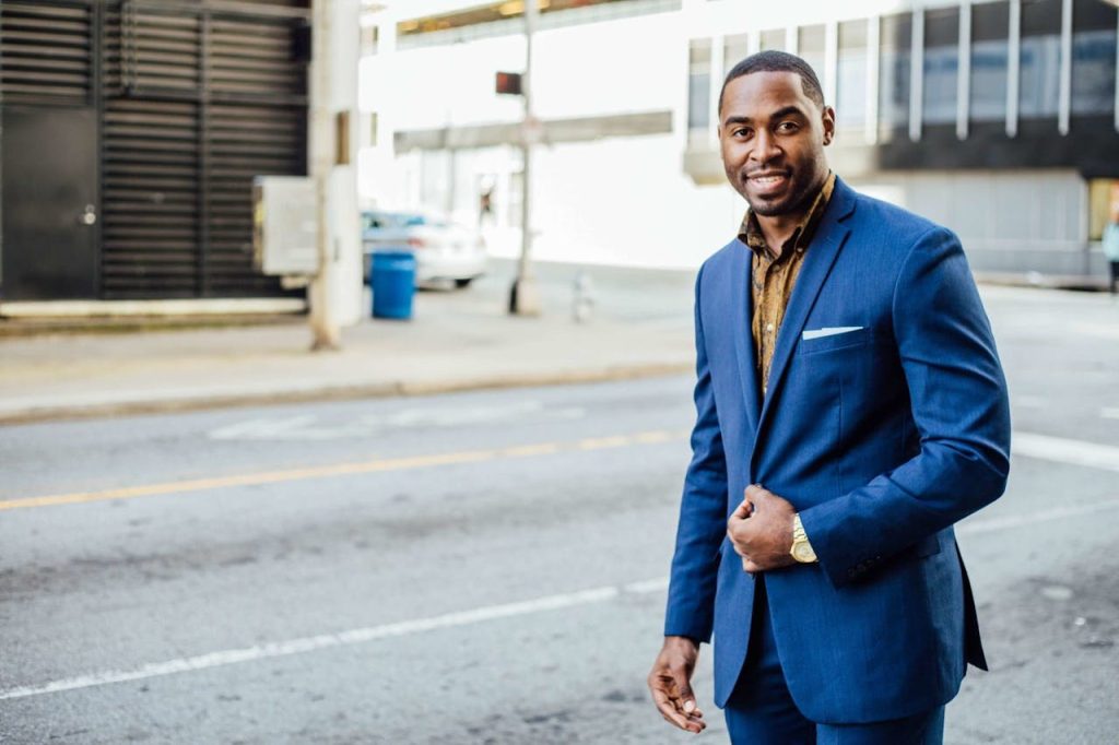 A confident man in a blue suit standing calmly on a city street, showing self-assured and balanced masculine strength.