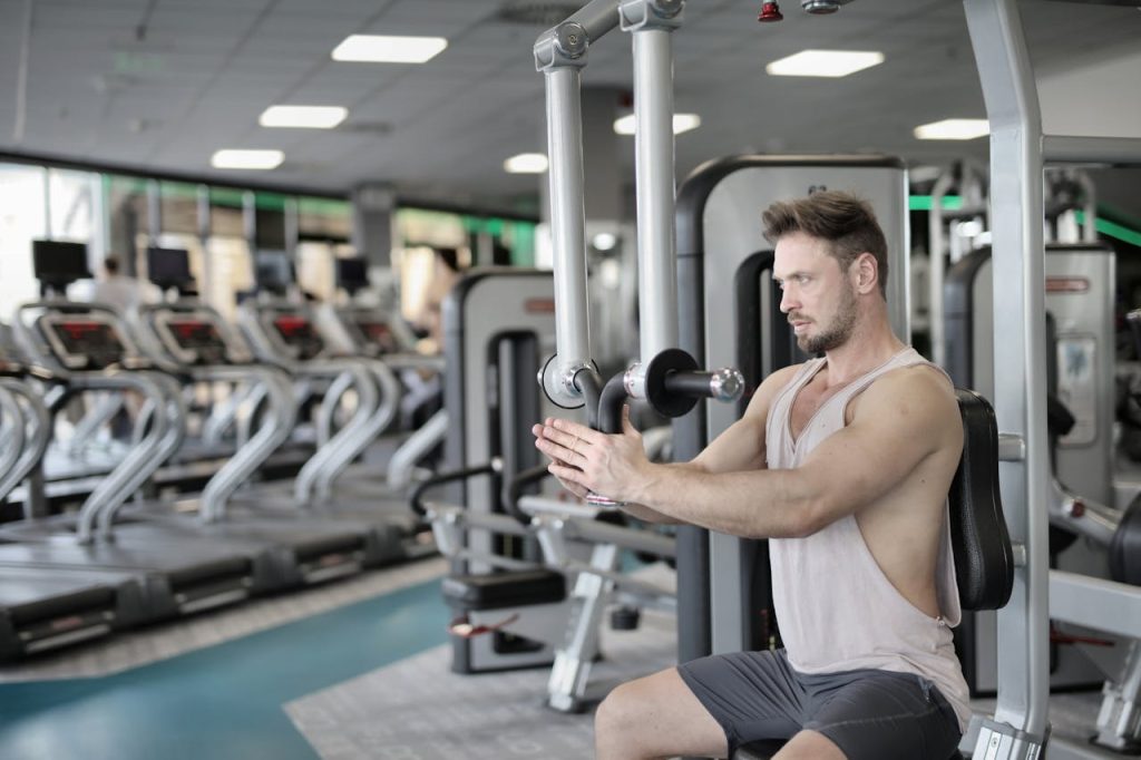 Man training on a chest press machine in a gym, representing physical strength as only one part of redefining manly strength.