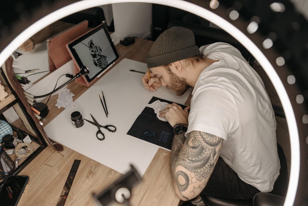 A man sketching detailed illustrations at a desk under focused lighting, representing creative outlets for men through drawing and visual expression.