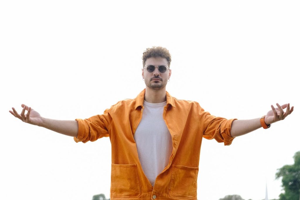 A calm and confident man standing with open arms in a receiving posture, symbolizing courage, vulnerability, and redefining manly strength.