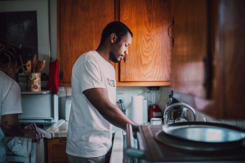 Man helping a younger person in a kitchen, symbolizing finding purpose as a man through mentorship, responsibility, and service.