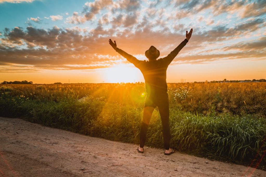 Man standing outdoors at sunrise with arms raised, symbolizing recovery, hope, and a new beginning after porn addiction.