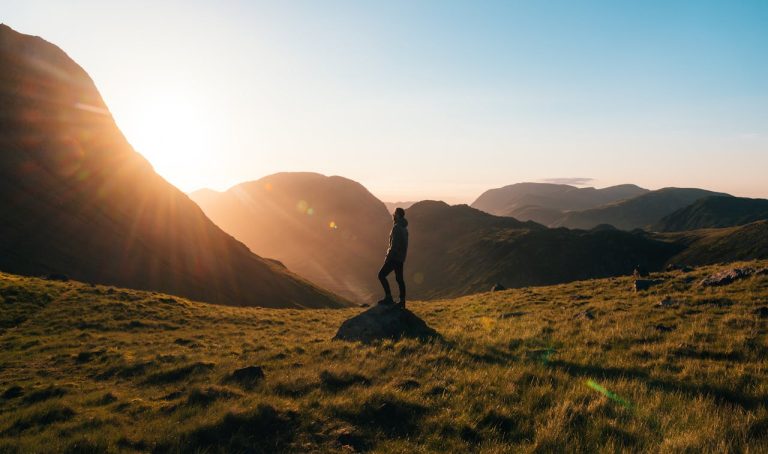 Man standing alone on a mountain ridge at sunrise, symbolizing reflection, direction, and finding purpose as a man.