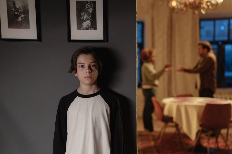 Child standing alone in the foreground while parents argue in the background, illustrating childhood’s impact on love life and adult relationships.