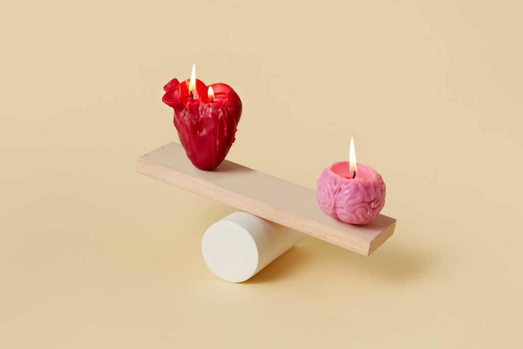 Balance scale with heart and brain candles, symbolizing healthy versus toxic masculinity and the balance between emotion and reason.