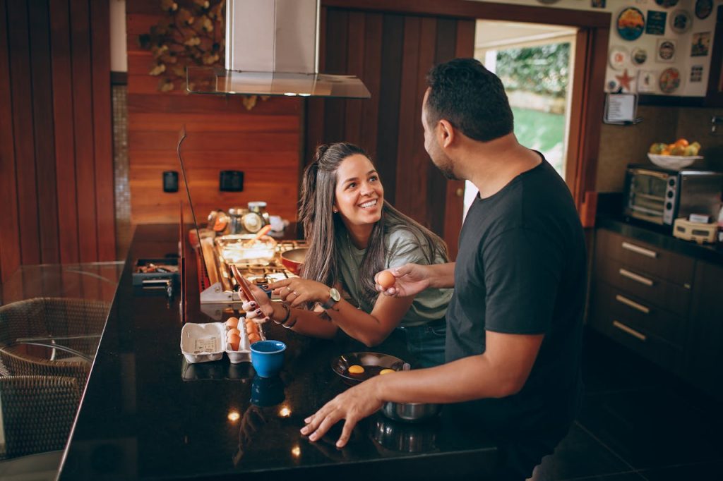 Couple cooking together in a kitchen, smiling and interacting playfully, illustrating intimacy beyond sex through shared activities and emotional connection.